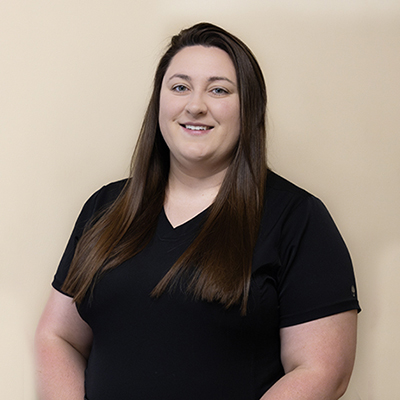 A woman in a black polo shirt is posing for the camera with a slight smile, standing against a light-colored background.