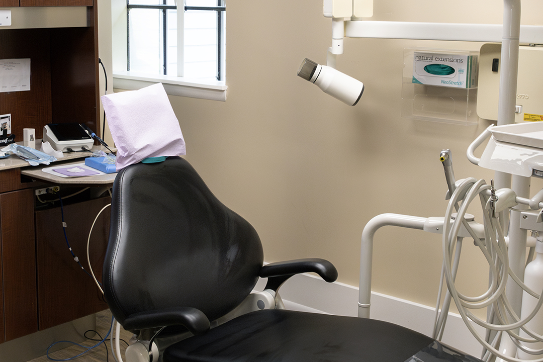 A dental office with a chair, desk, and medical equipment.