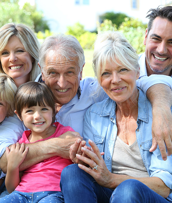 The image shows a family of five, including two adults and three children, posing for a photo outdoors during the day.