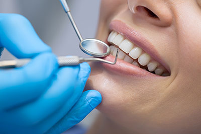 The image shows a person sitting in a dental chair, receiving dental care with a smile.