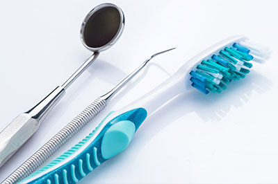 A collection of dental tools, including a toothbrush and dental instruments, displayed on a white surface.