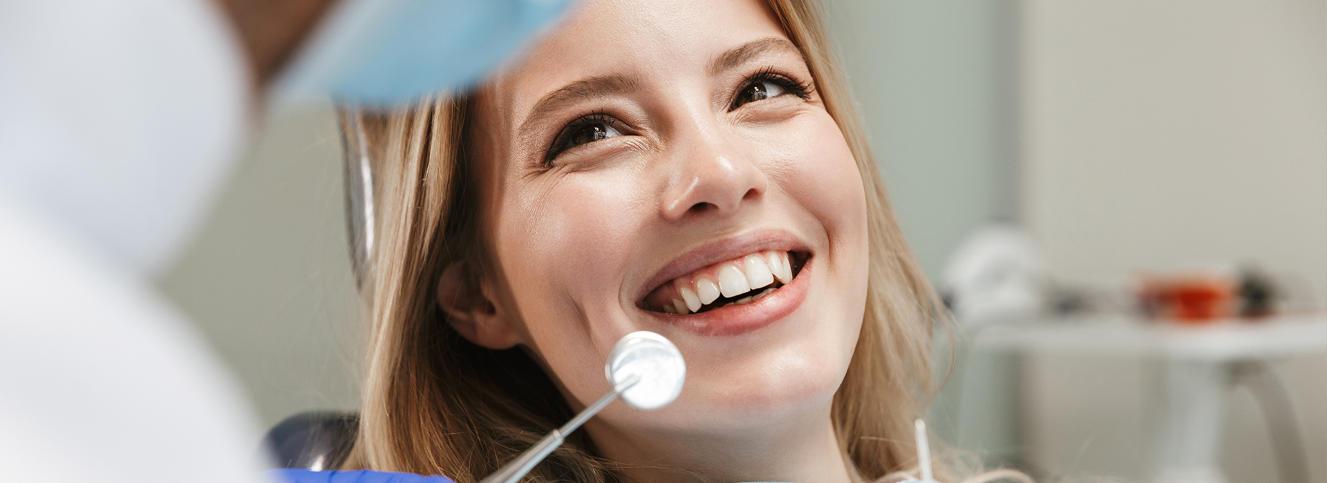 Woman smiling at camera with dental equipment in background.