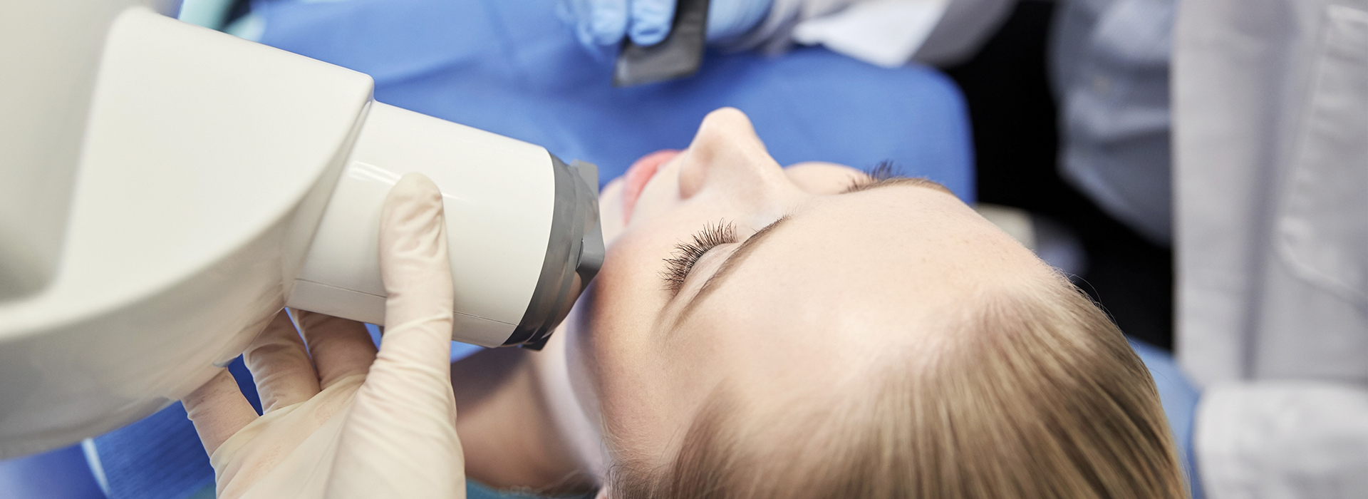 A person receiving a dental implant examination with a dentist using a digital scanner.