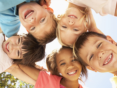 A group of children smiling and posing for a photo with their hands on each other s shoulders.